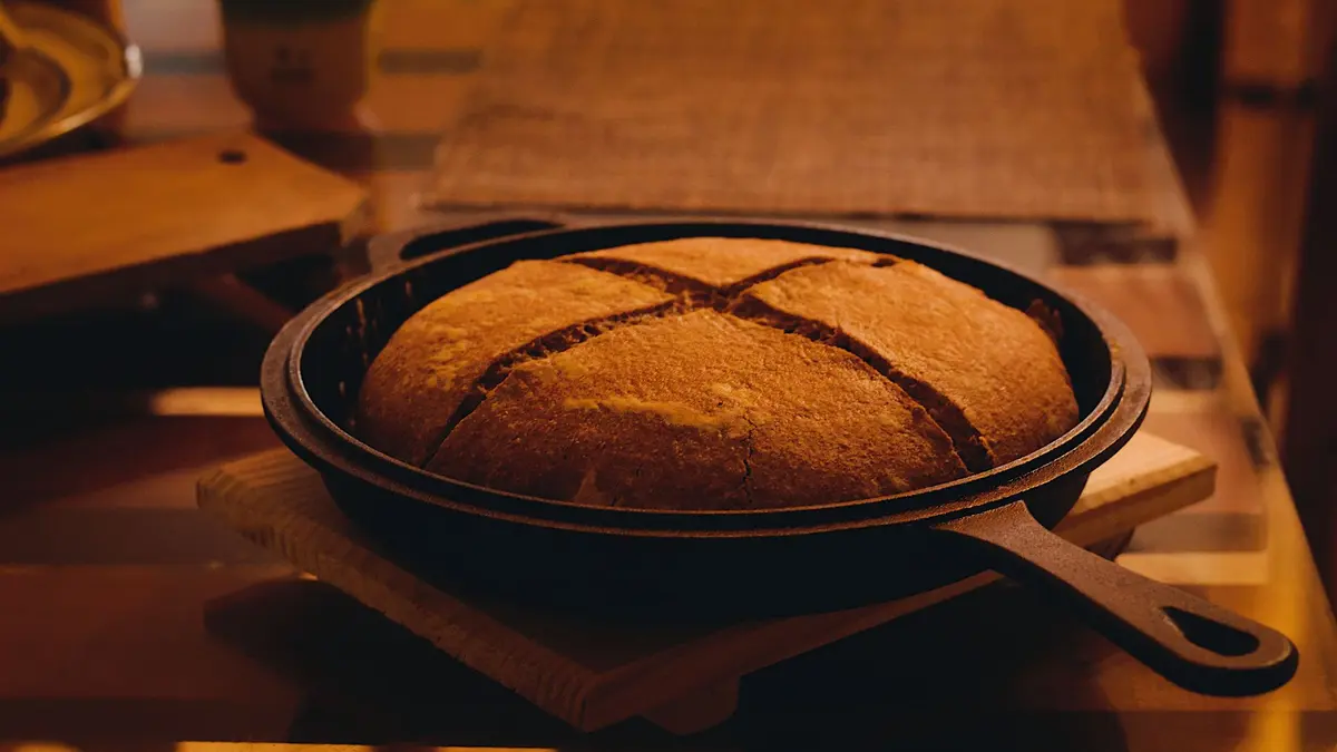 Zuurdesembrood met kruisvormige insnijding in een gietijzeren pan