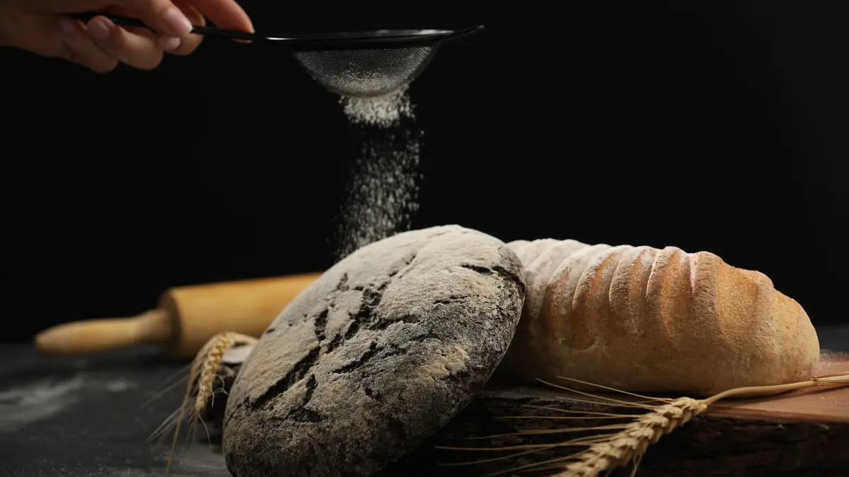 Bloem gezeefd over een vers brood