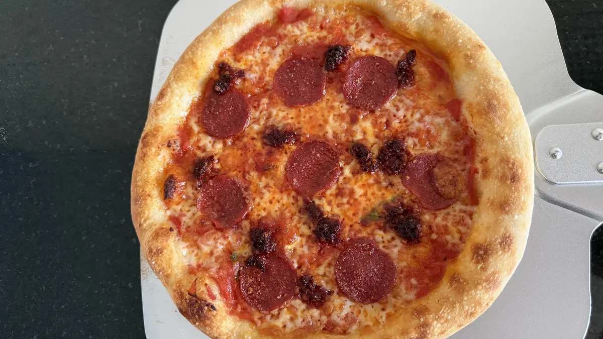 Zelfgebakken pepperonipizza met 'nduja op een pizzaschep