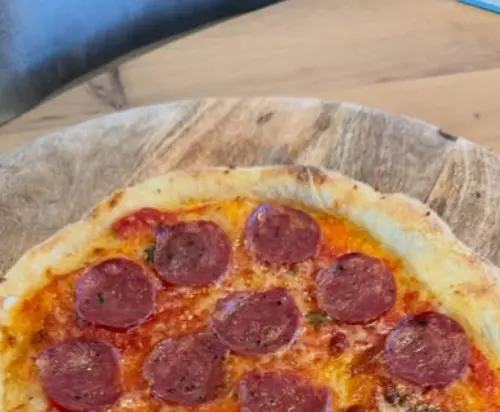 Zelfgebakken pepperonipizza op een houten plank