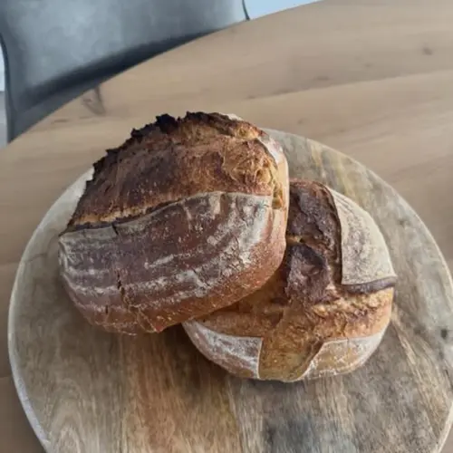 Twee zuurdesem boules op een ronde houten snijplank